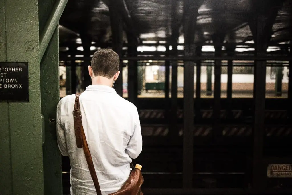 man waiting for subway with messenger bag