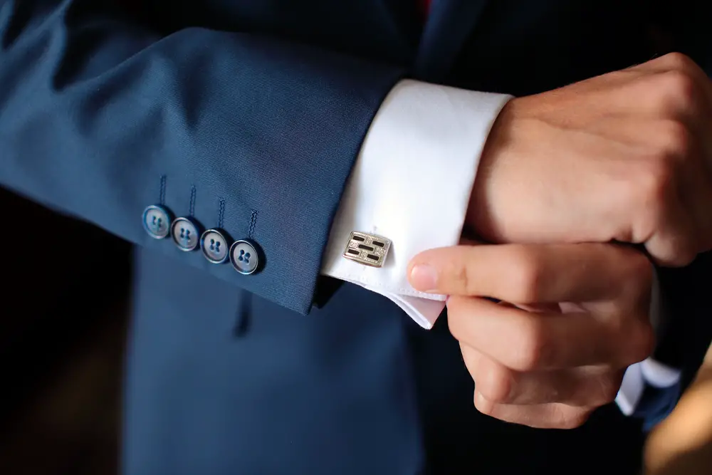 Article: How to wear cufflinks Image shows Hands of wedding groom getting ready in suit